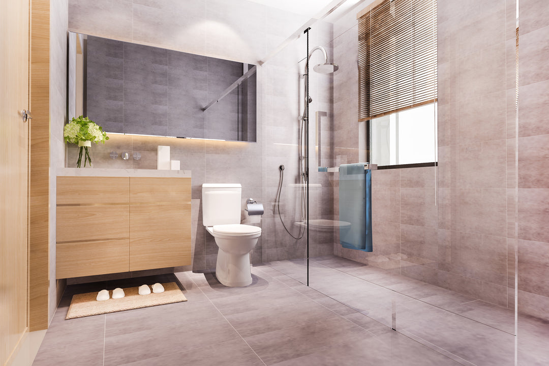 Modern bathroom with marble tile walls, a floating wooden vanity, glass-enclosed shower, and natural light, showcasing sleek and minimalist design.